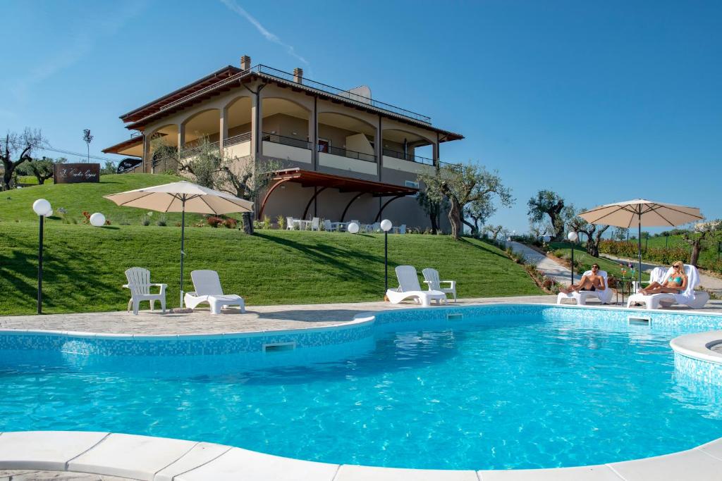 einen Pool mit Stühlen und Sonnenschirmen vor einem Haus in der Unterkunft Cataleya Resort & Spa in Notaresco