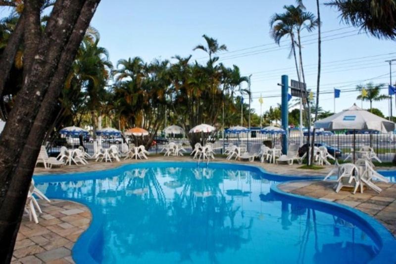 a large swimming pool with chairs and umbrellas at Hotel Atlantico Sul in Caraguatatuba