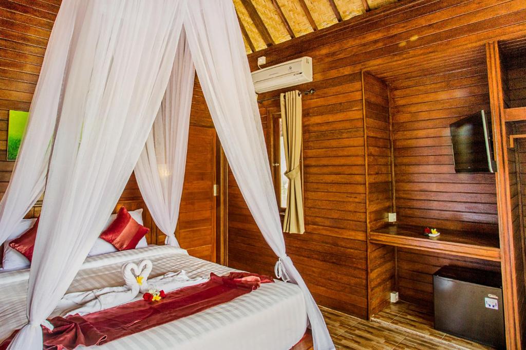 een slaapkamer met een bed met een klamboe bij Mimpi Cottages in Nusa Lembongan