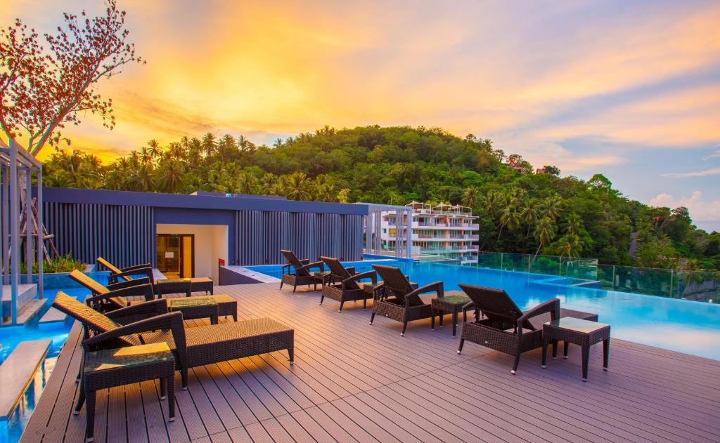 a deck with chairs and tables and a swimming pool at The Aristo Beach by Holy Cow, studio, without kitchen, mountain view in Surin Beach
