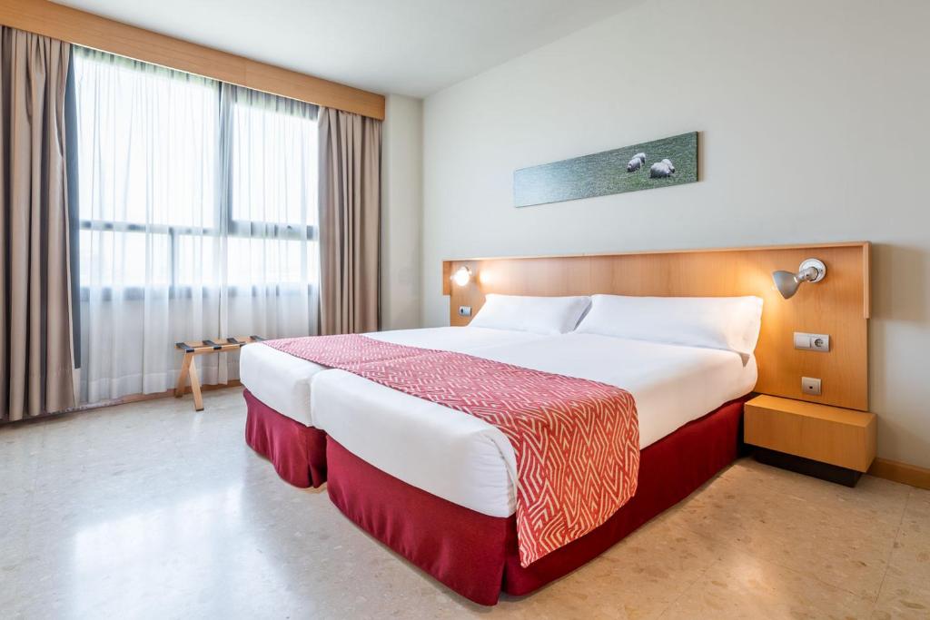 ein Hotelzimmer mit einem großen Bett und einem großen Fenster in der Unterkunft Aparthotel Exe Campus San Mamés in León