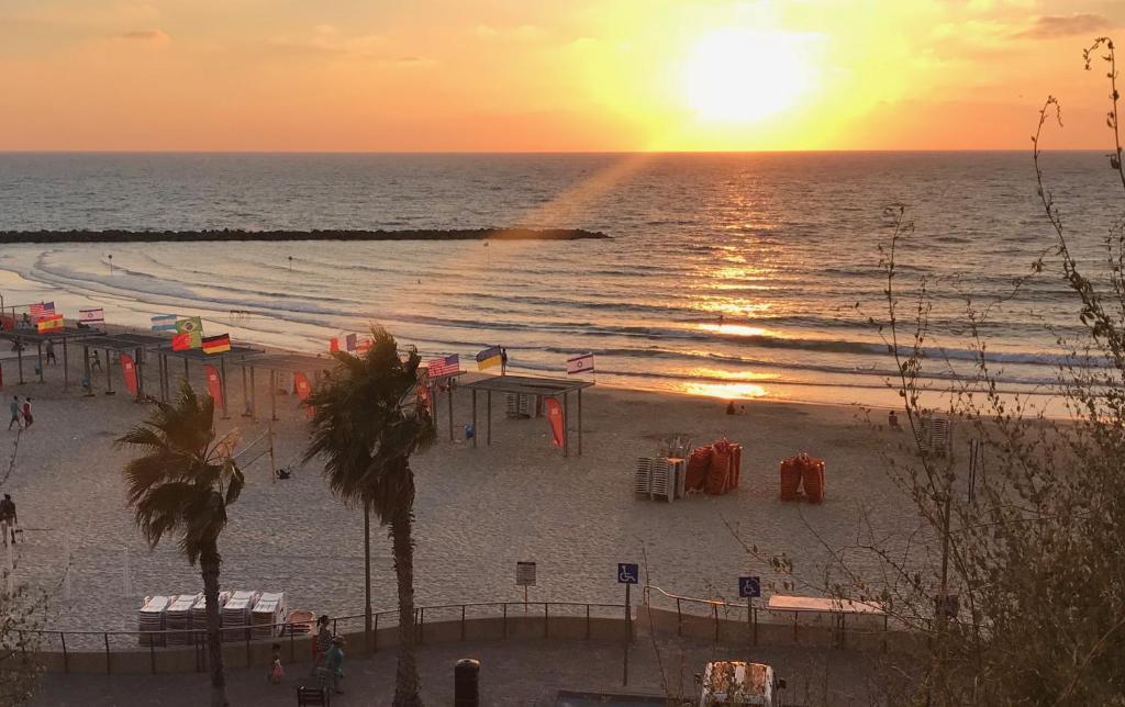 a beach with the sun setting over the ocean at Lucy in Netanya