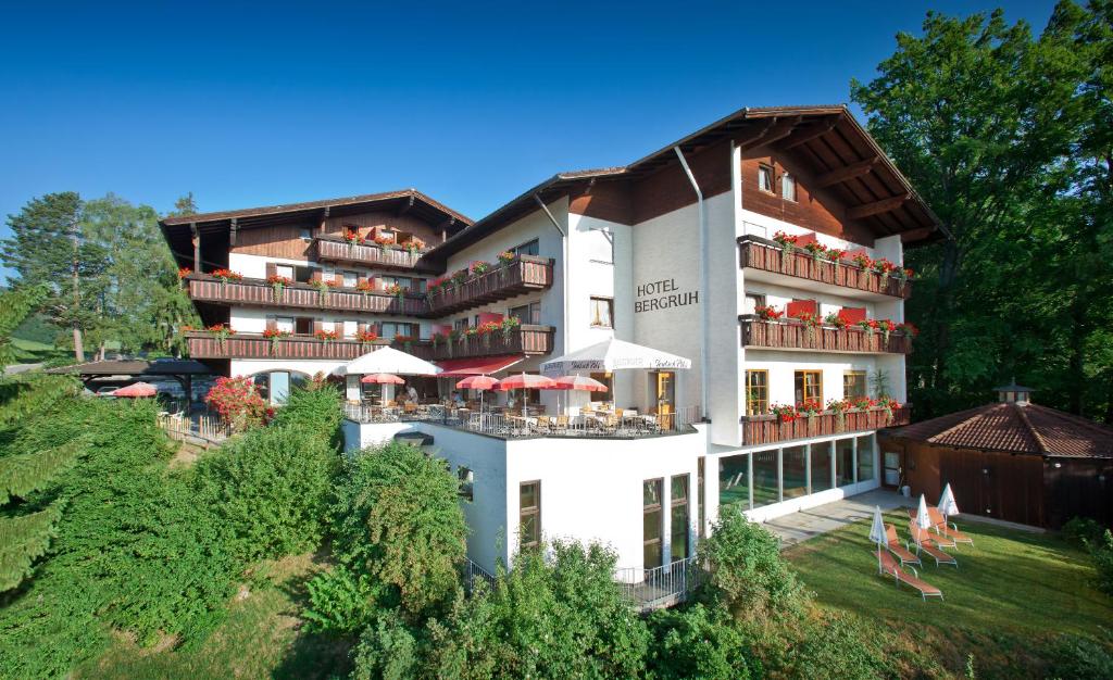 ein großes weißes Gebäude mit Tischen und Sonnenschirmen in der Unterkunft Hotel Bergruh in Füssen