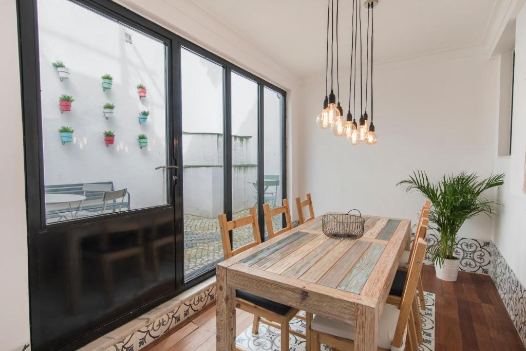 een eetkamer met een houten tafel en een groot raam bij Bica Patio 3BDR Duplex by LovelyStay in Lissabon