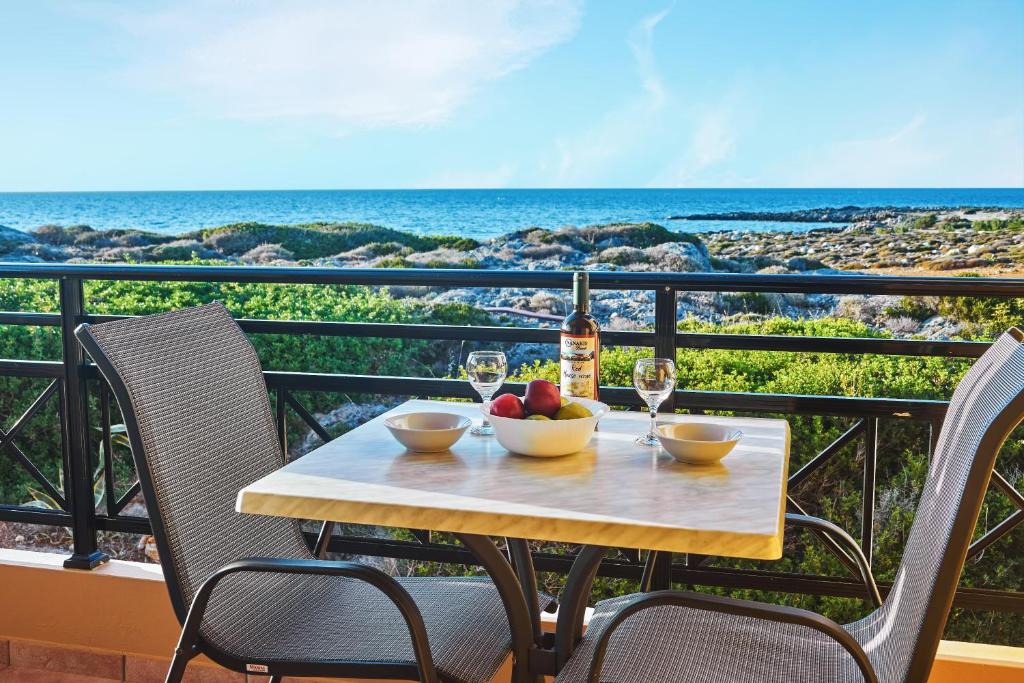 a table with a bottle of wine and fruit on a balcony at Nanakis Beach Apartments in Stavros