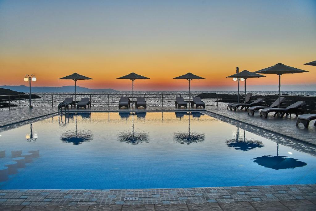 a pool with tables and chairs and umbrellas at Nanakis Beach Apartments in Stavros