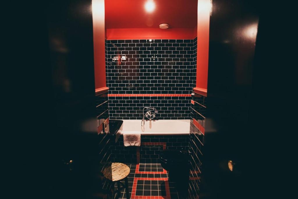 La salle de bains est pourvue d'un lavabo et d'un mur rouge. dans l'établissement La Mondaine, à Paris