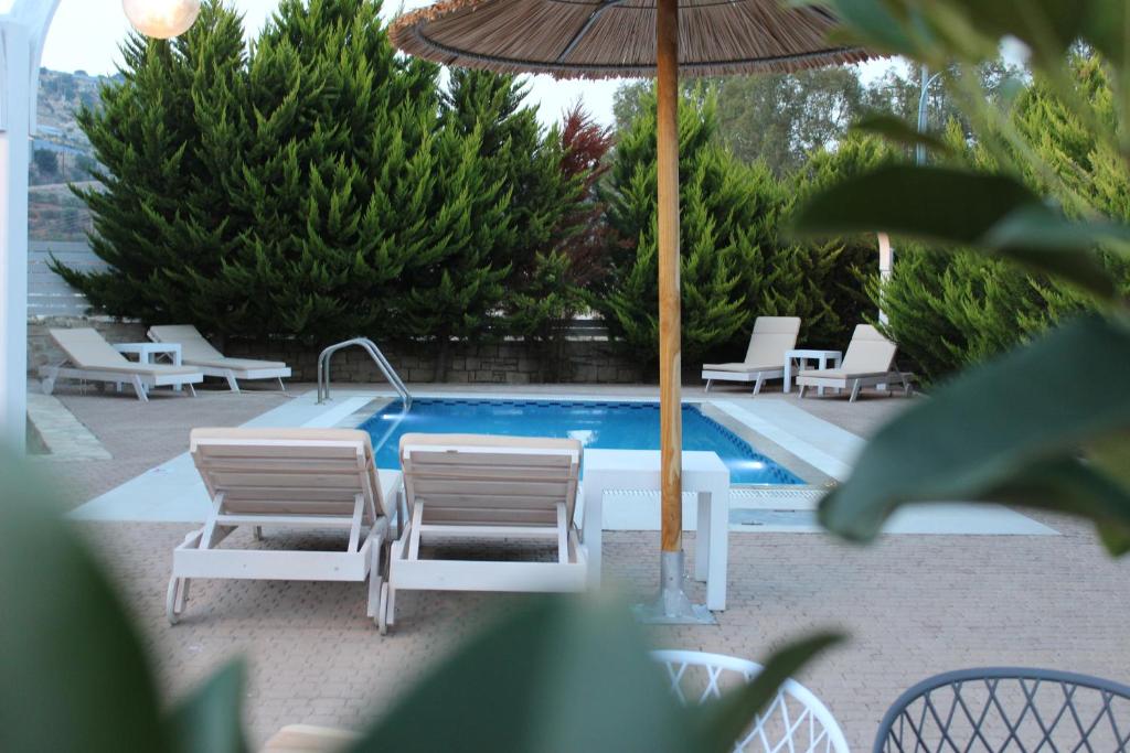 una piscina con 2 sillas y una sombrilla en Carob Villa en Moírai