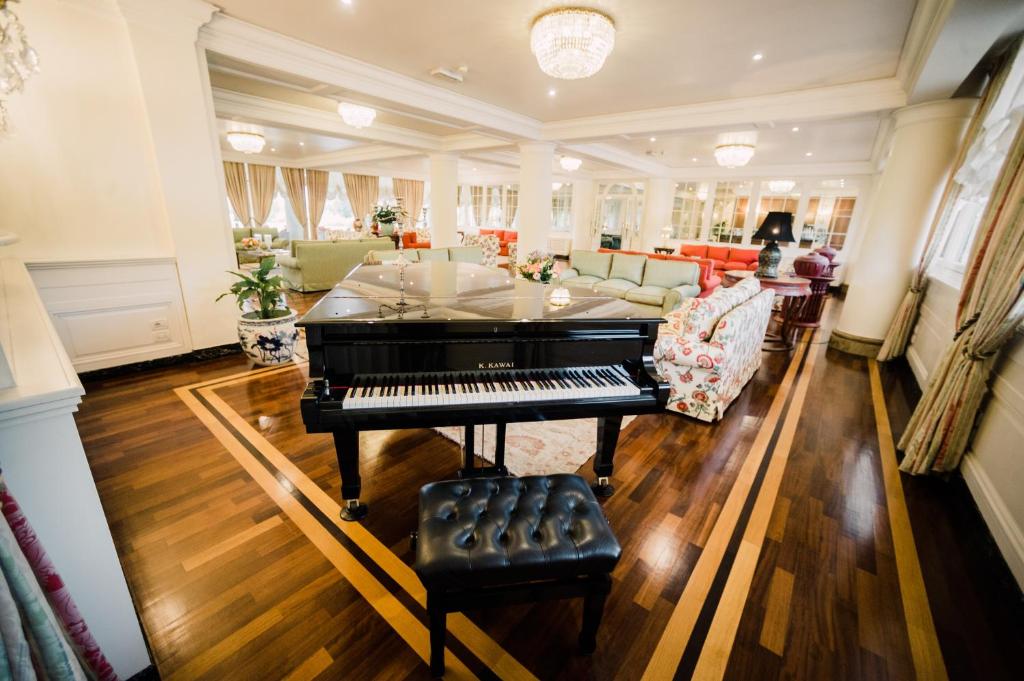ein Wohnzimmer mit einem Klavier und einem Sofa in der Unterkunft Versilia Golf Resort in Forte dei Marmi