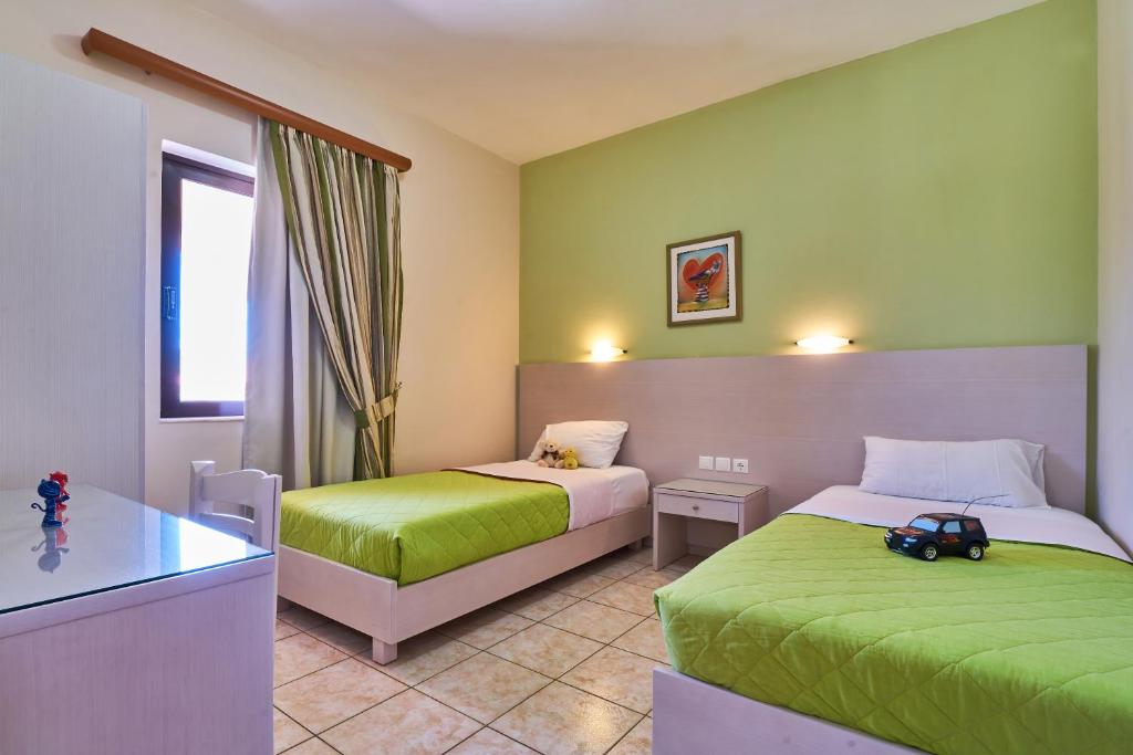 a hotel room with two beds with green sheets at Nanakis Beach Apartments in Stavros