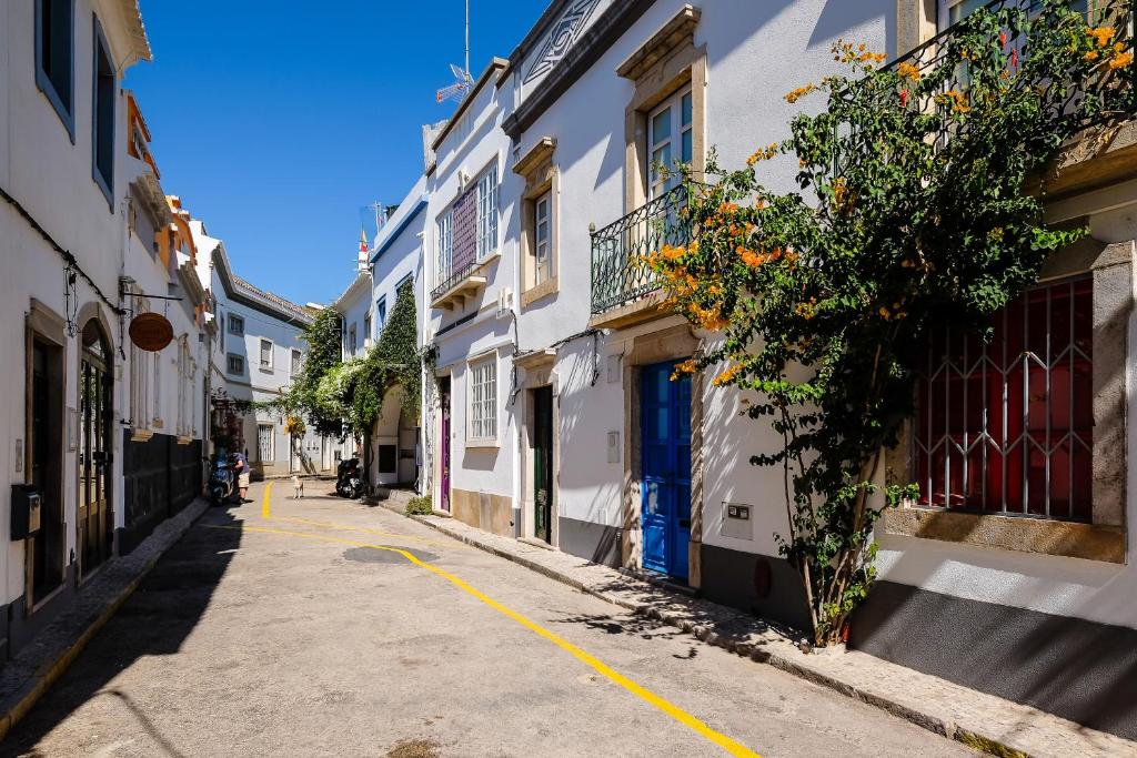a narrow alley with white buildings and a blue door at Casa Séqua in Tavira