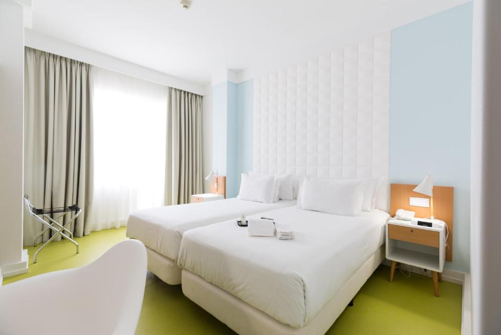 a hotel room with a large white bed and window at Legendary Porto Hotel in Porto