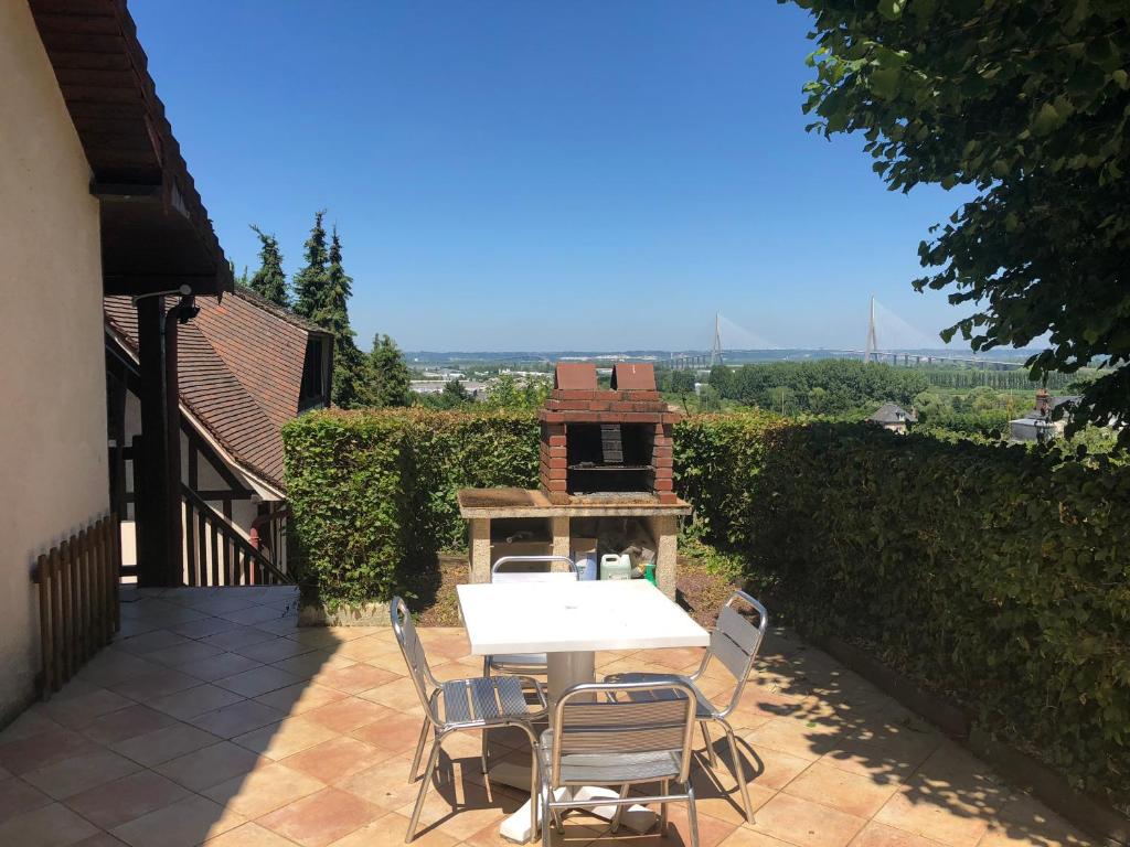 a table and chairs on a patio with a grill at Aux lettres du lavoir in La Rivière Saint Sauveur