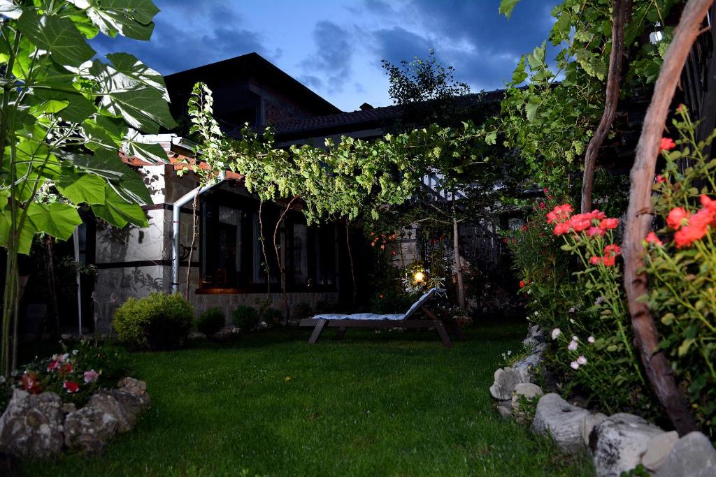 a garden with a bench in the middle of a yard at Trenchova Guest House in Bansko