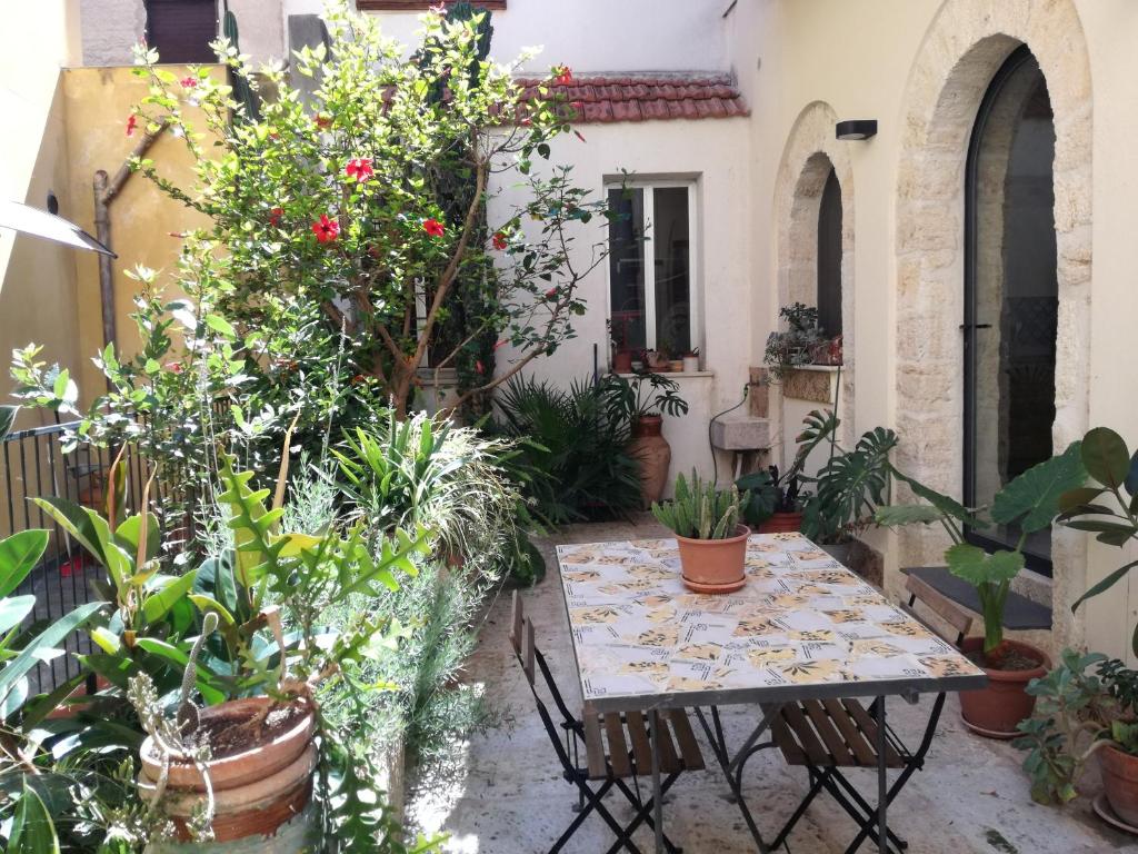 un patio avec une table et de nombreuses plantes dans l'établissement Residenza Bagolino, à Alcamo