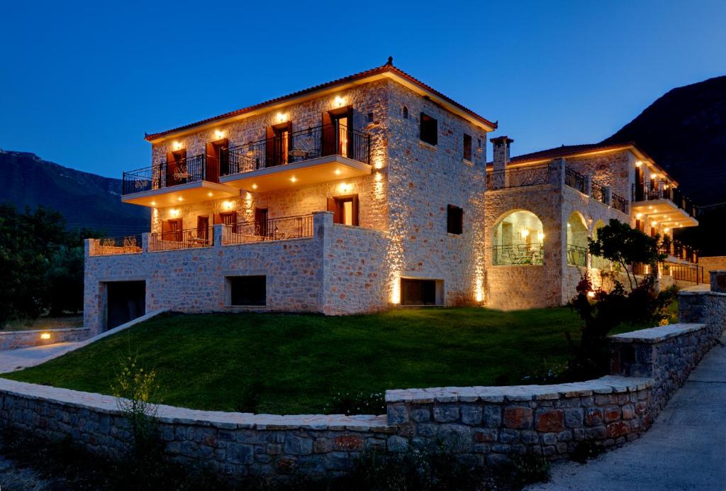 a large stone house with lights on it at night at Byzantinon Hotel in Leonidion