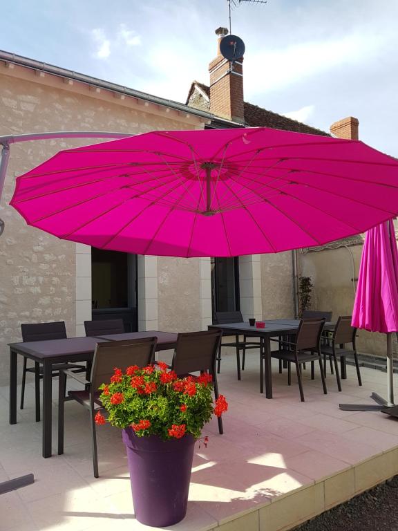 um grande guarda-chuva rosa num pátio com mesas e flores em Chez Onna em Theneuil