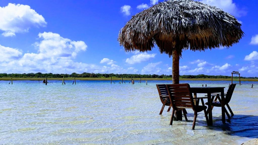 una mesa y sillas bajo una sombrilla en el agua en Recanto Vendramel Bezerra, en Jijoca de Jericoacoara