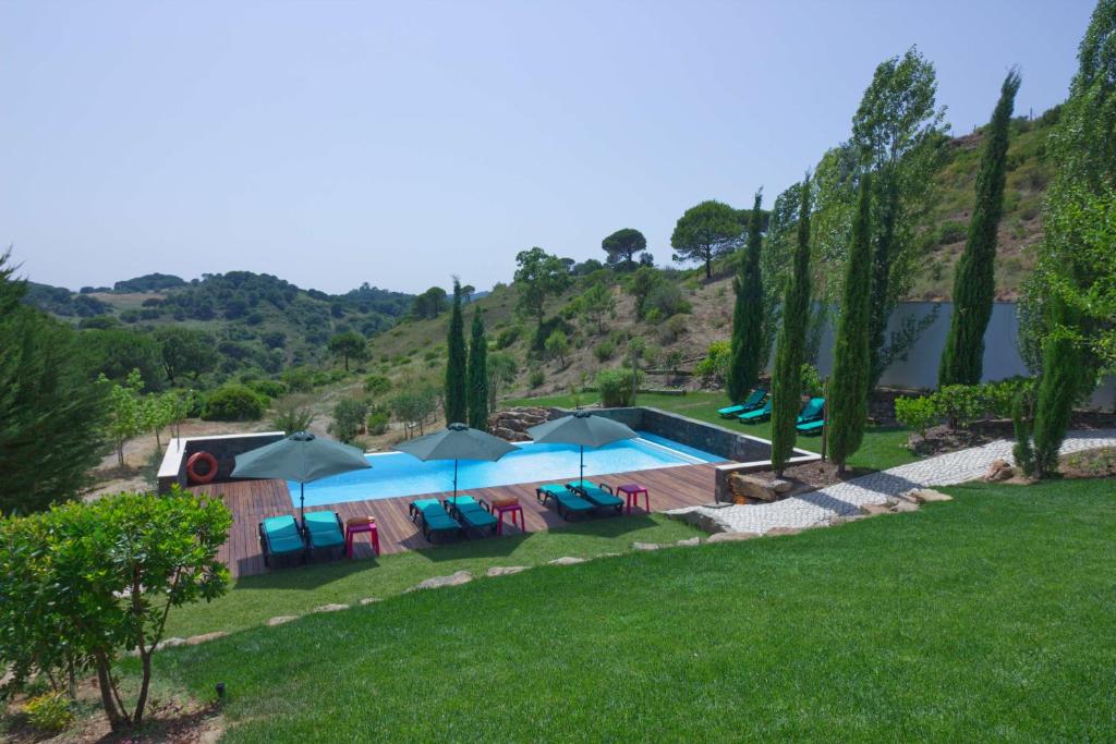 una piscina con sombrillas y sillas en un patio en Halma - Nature & Sea, en Setúbal