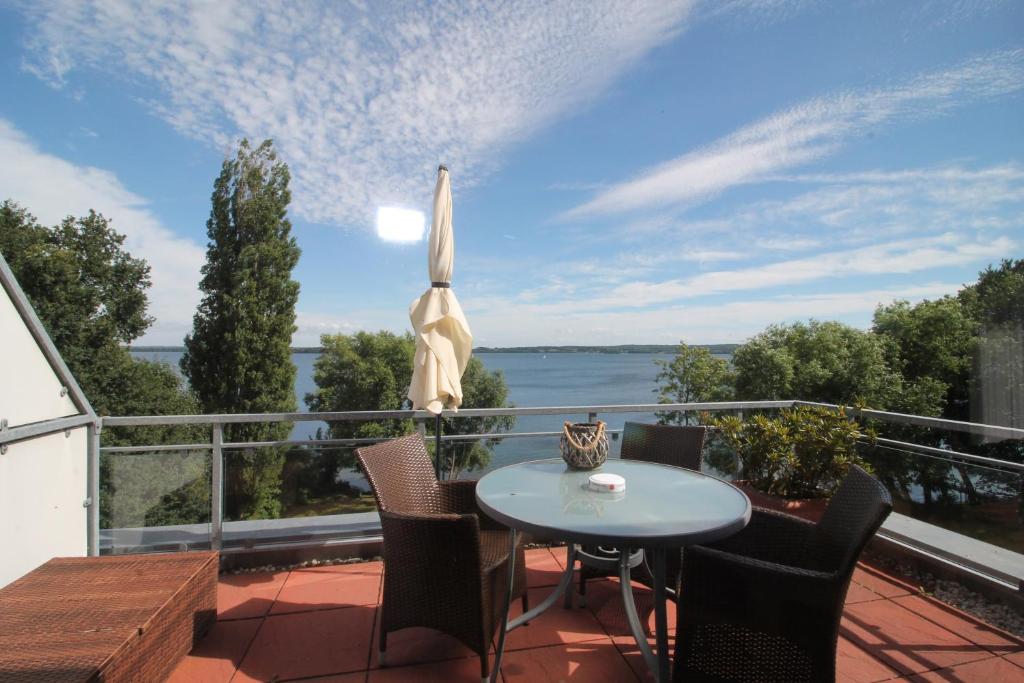 un patio con tavolo e sedie sul balcone. di Penthouse am Großen Plöner See ad Ascheberg