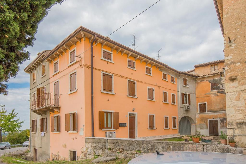 a large orange building with a stone wall at Valpolicella Homes Recioto Apartment in SantʼAmbrogio di Valpolicella