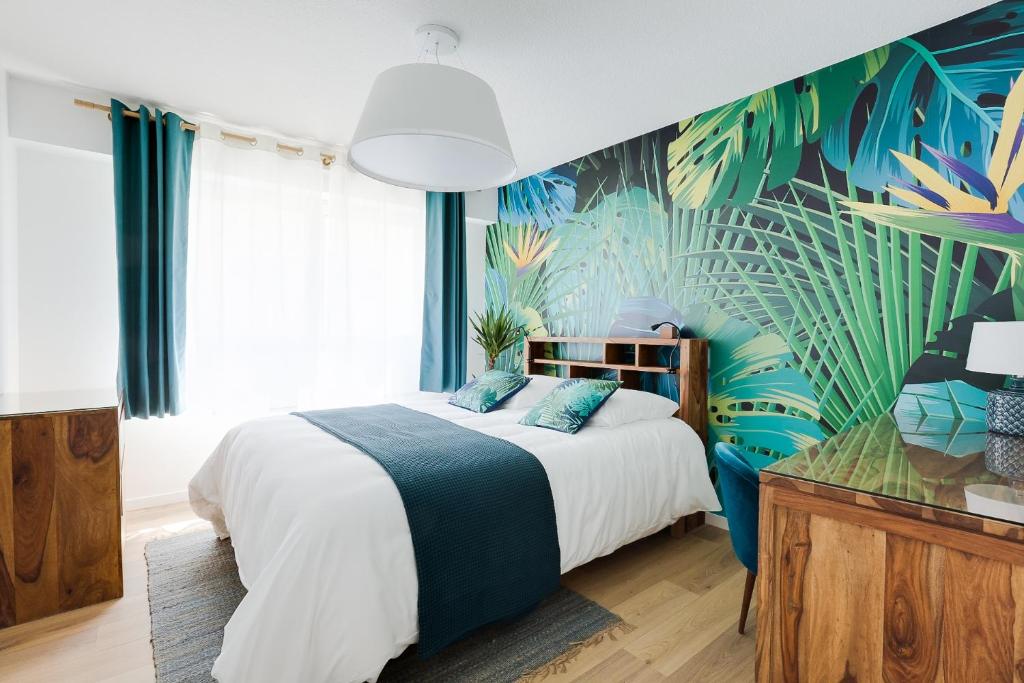 a bedroom with a large bed with a tropical wallpaper at Naeva Feng Shui in Strasbourg