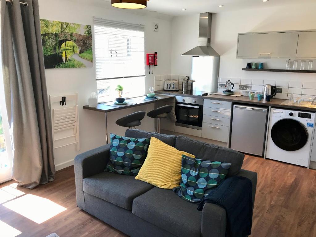 a living room with a couch and a kitchen at Upper Highview - Self Catering Apartment, fpventures Stroud in Stroud