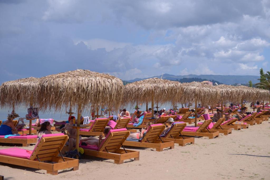 a group of beach chairs and straw umbrellas on a beach at Argilos in Sidari