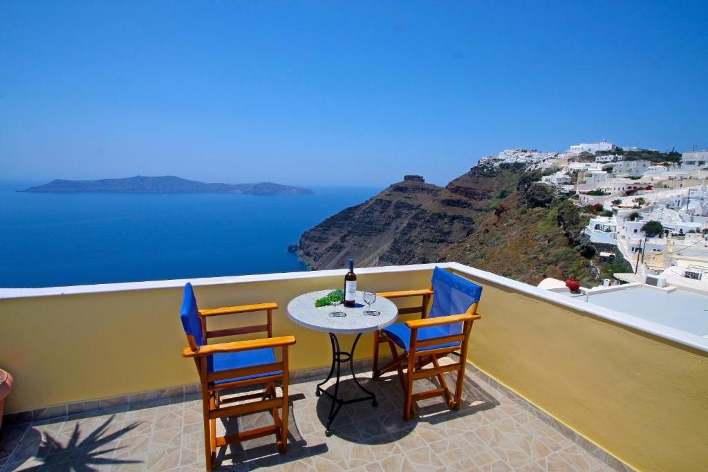 una mesa y sillas en un balcón con vistas al océano en Hotel Mylos, en Firostefani