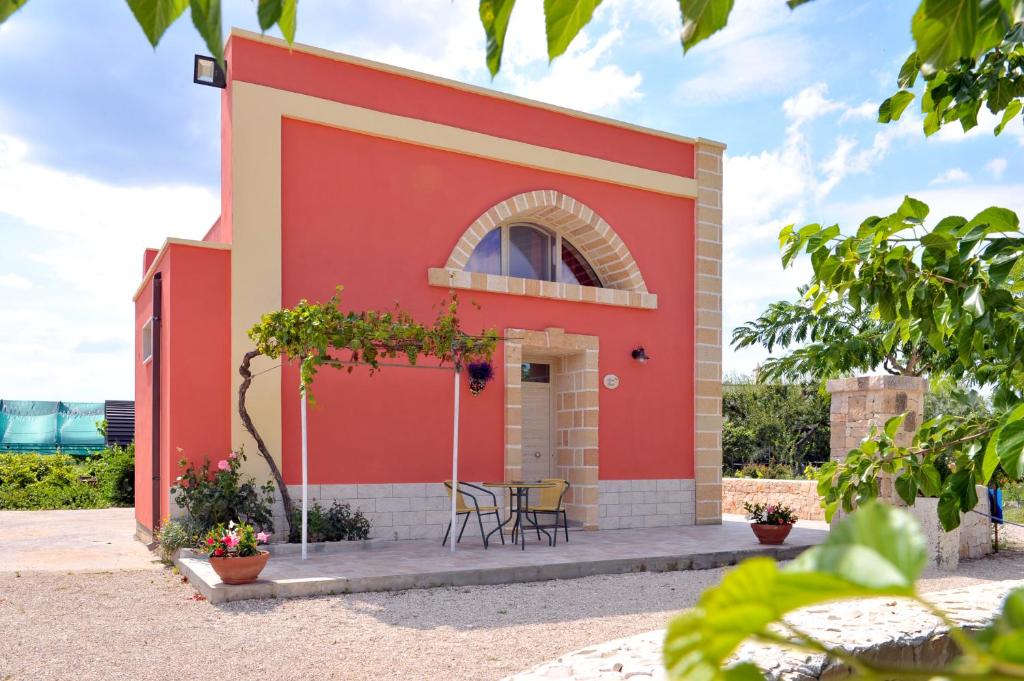 un bâtiment rouge avec une table et des chaises devant lui dans l'établissement Villa Ada Leverano, à Leverano