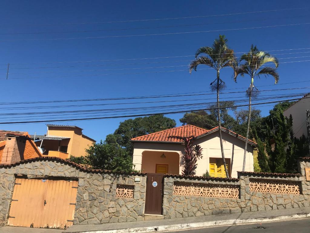 a house with a stone wall and a palm tree at Casa de Nara in São João del Rei