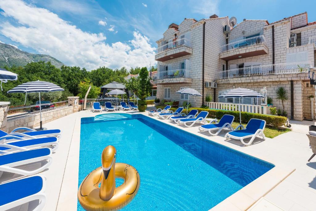 a swimming pool with chairs and a hotel at Villa Markoc in Cavtat