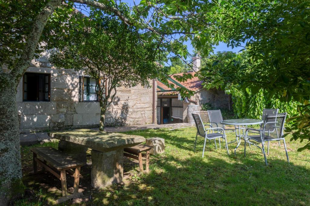 una mesa y sillas en un patio junto a un árbol en Asador de Roxos Casa Albardonedo, en Santiago de Compostela