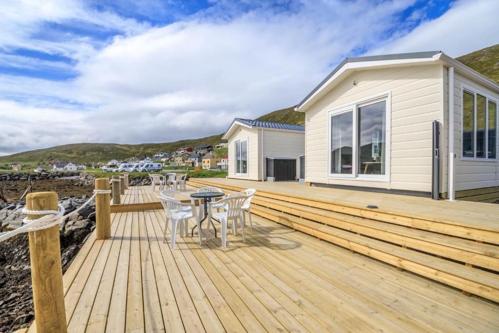 una terraza de madera con mesa y sillas en una casa en Seaside cabin Skarsvåg, en Skarsvåg