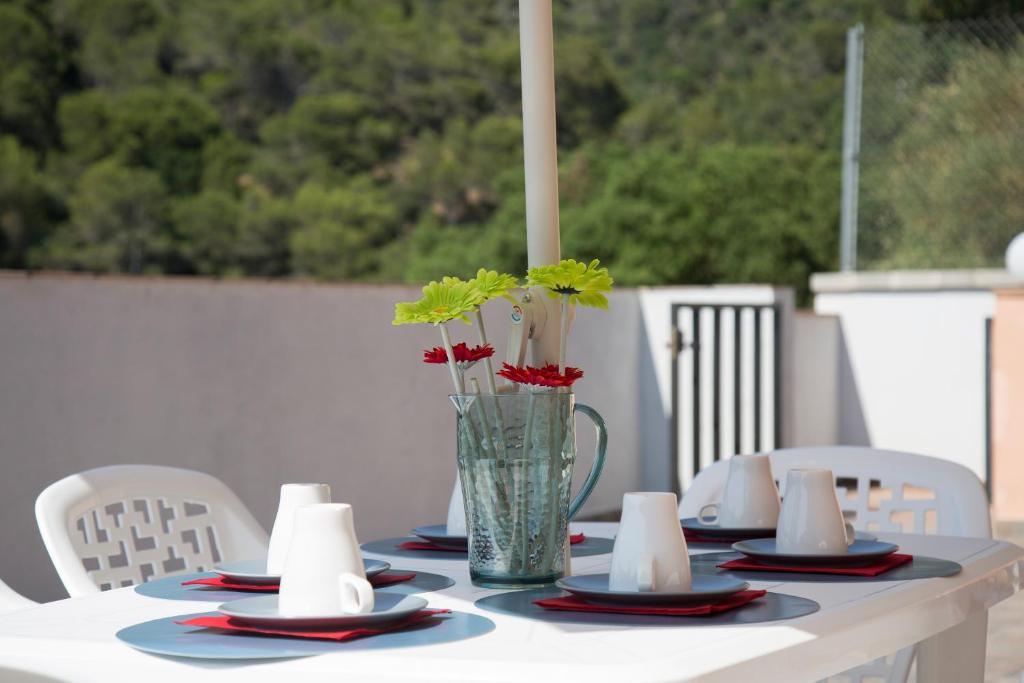 una mesa con platos y un jarrón con flores. en Home Family, en Tossa de Mar