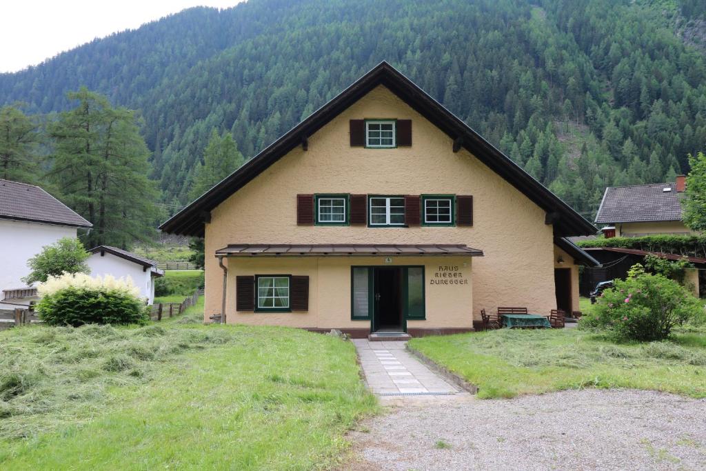 uma casa numa colina com montanhas ao fundo em Ferienhaus Rieger em Mallnitz