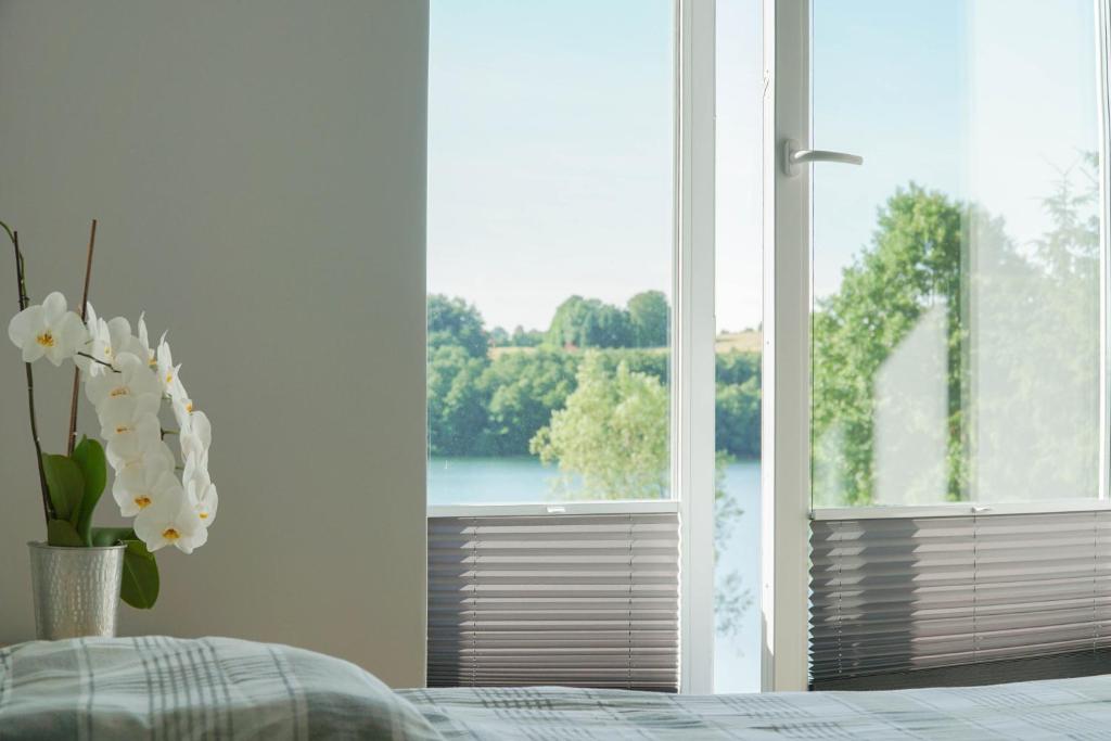 フミエルノにあるPrzystań Raduńskaのベッドルーム1室(水辺の景色を望む大きな窓付)
