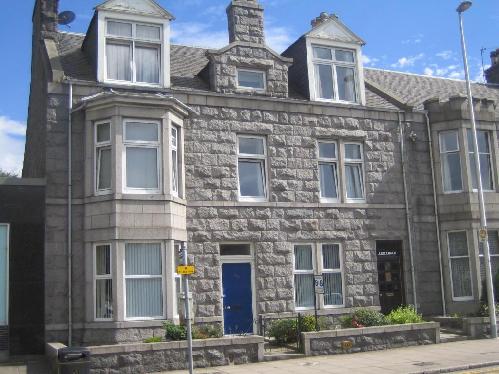 an old stone house with a blue door at Armadale Guest House in Aberdeen