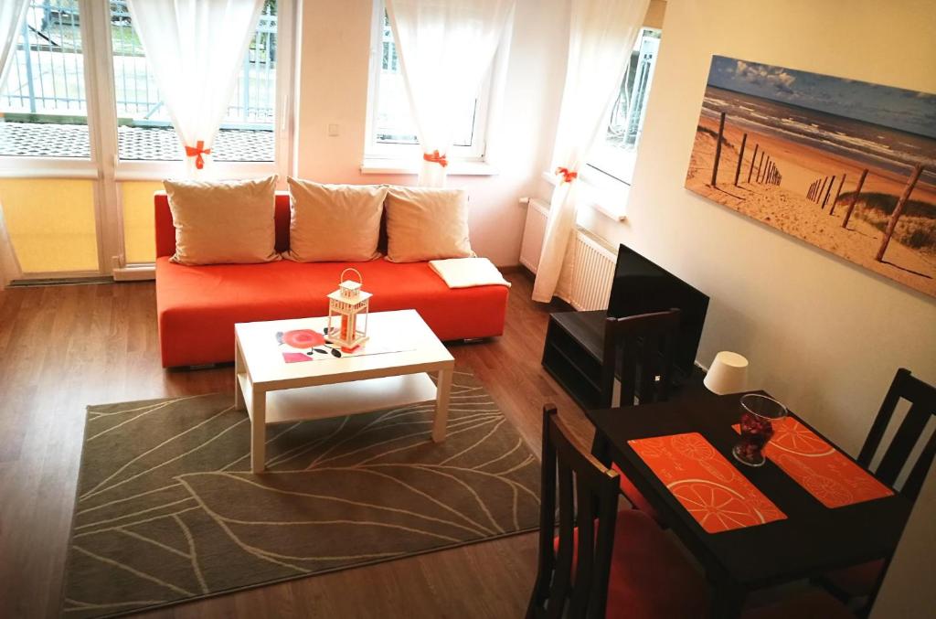 a living room with a red couch and a table at Apartamenty Międzymorzem in Krynica Morska