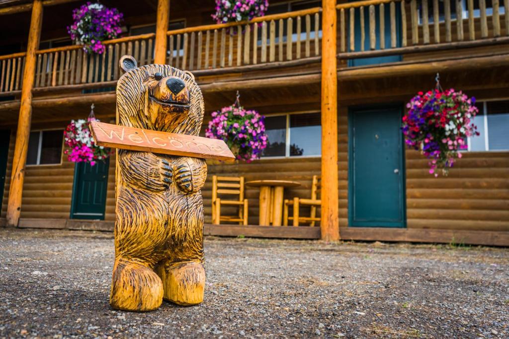 una estatua de oso de madera frente a un edificio en River Lodge, en Island Park