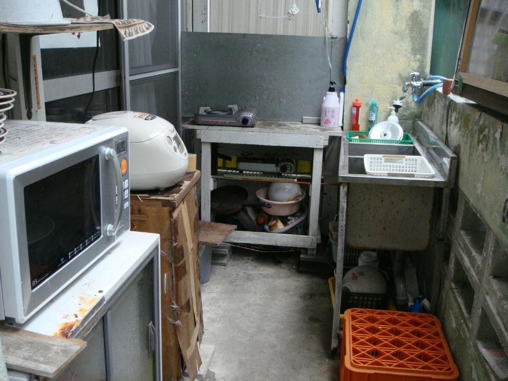 una cocina desordenada con fregadero y microondas en Guest House Green House, en Naha