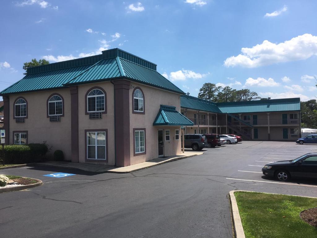 a building with a green roof and a parking lot at Deluxe Inn in Galloway