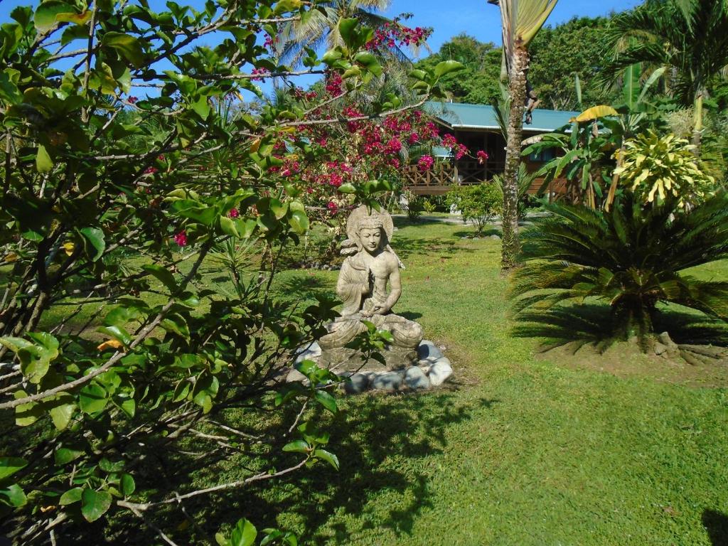 a statue of a monkey sitting on a rock in the grass at J and H Garden Cabinas in Bocas del Toro