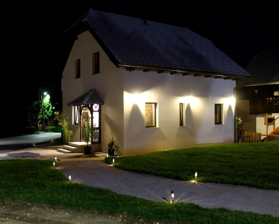 una casa blanca por la noche con luces en la hierba en The Jungle Apartments and Rooms (Vila Džungla), en Bled
