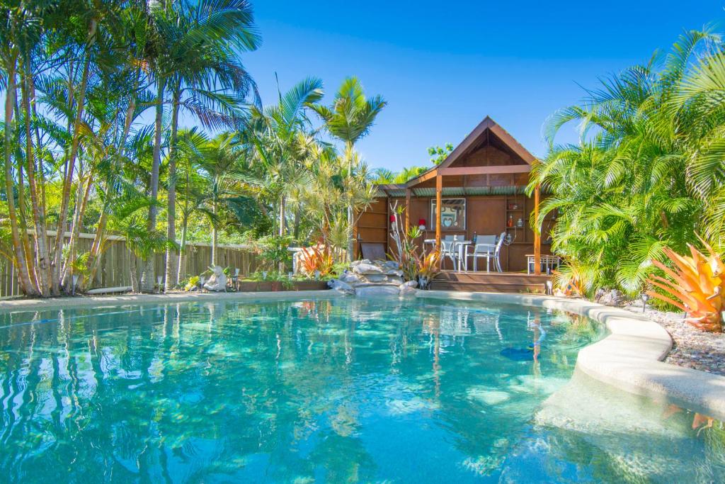 a swimming pool in front of a house with palm trees at Gina‘s Place in Peregian Beach