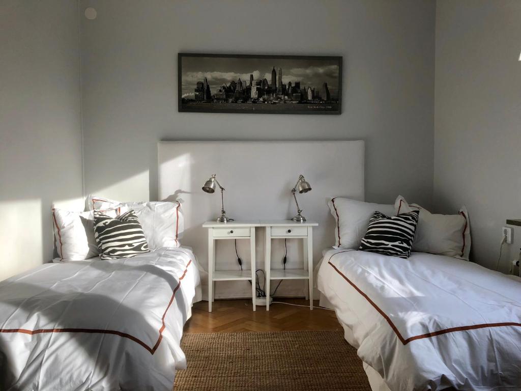 a bedroom with two beds and a table with a picture on the wall at Central Stockholm with Free Airport Pickup in Stockholm