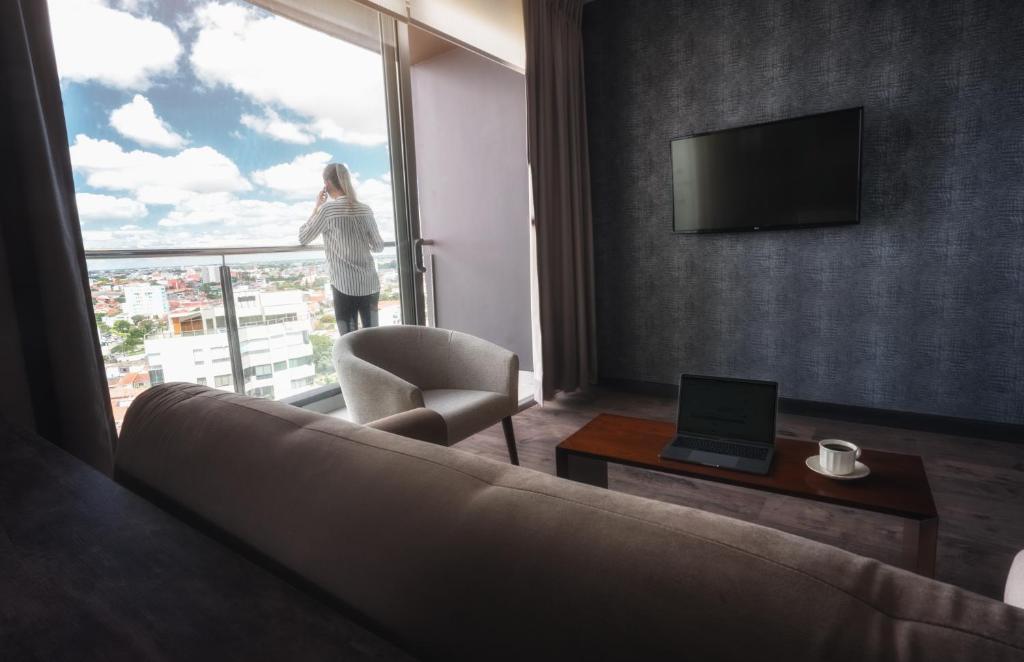 a woman looking out the window of a hotel room at Urban Suites Apart Hotel in Santa Cruz de la Sierra