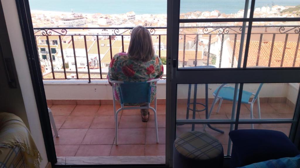 ナザレにあるCasa da praiaのバルコニーの椅子に座る女性
