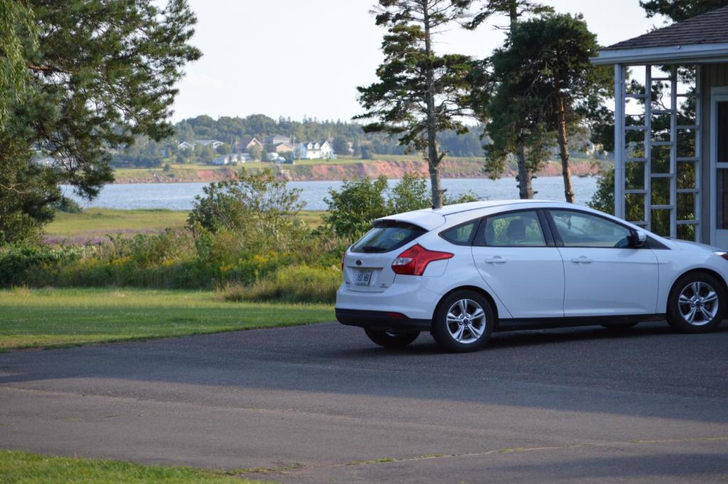 a white car parked in front of a house at Sunny Isle Motel in Summerside