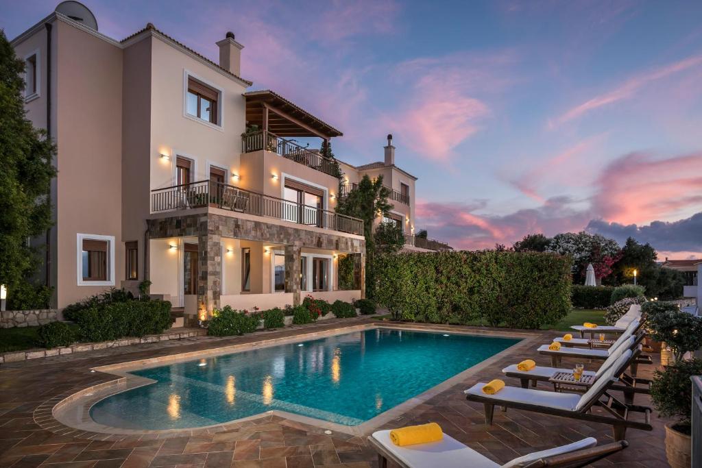 Villa con piscina frente a una casa en Caneva Luxury Villa, en Tavronitis